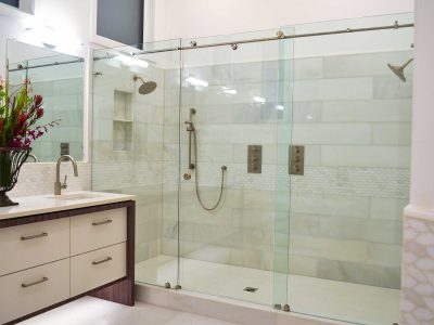 Huge 1950s master white tile and porcelain tile ceramic tile, white floor and double-sink bathroom with flat-panel cabinets, white cabinets, a two-piece toilet, white walls, an integrated sink, quartz countertops, white countertops and a freestanding vanity.
