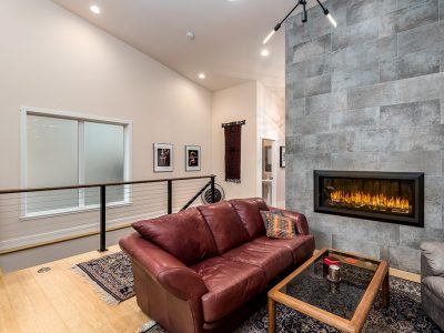Large mid-century modern open concept light wood floor and brown floor living room remodel in Portland with white walls, a hanging fireplace and a tile fireplace.